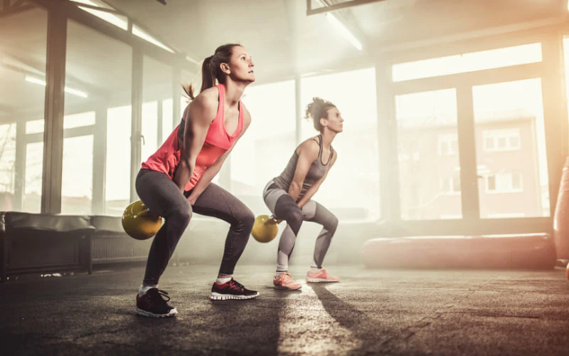 Deux pratiquants réalisant des squats avec kettlebell