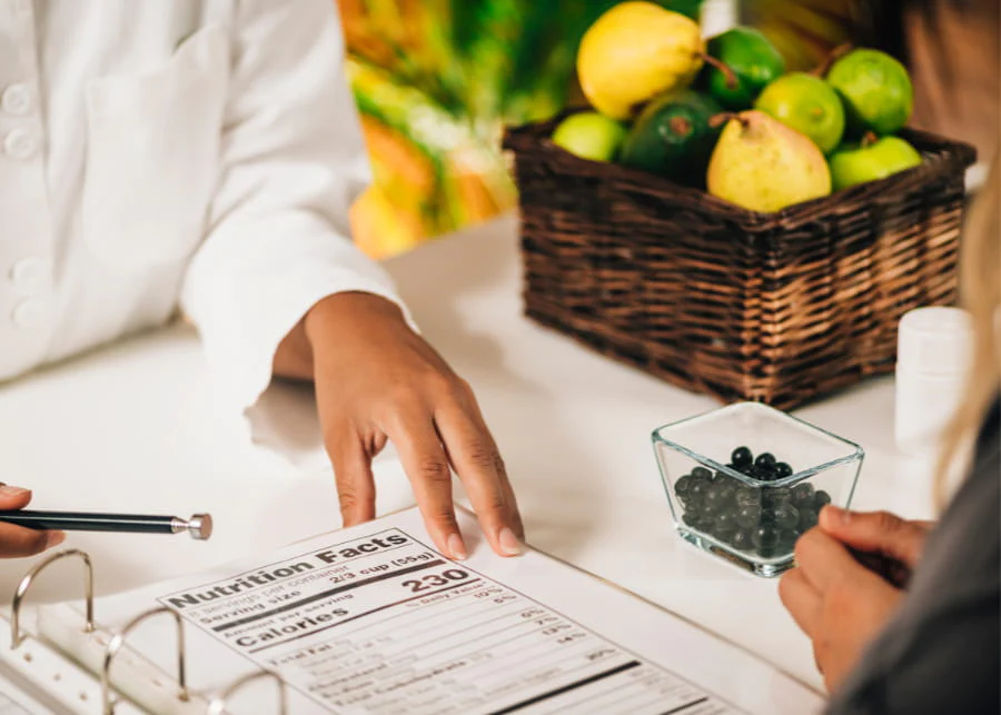 Personne consultant une étiquette nutritionnelle près d'une corbeille de fruits