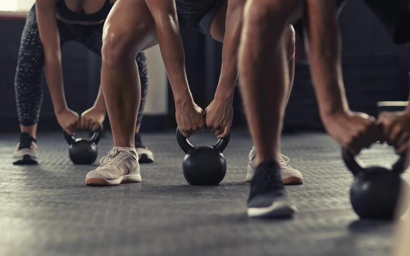 Groupe réalisant des soulevés de terre avec kettlebells dans une box de CrossFit