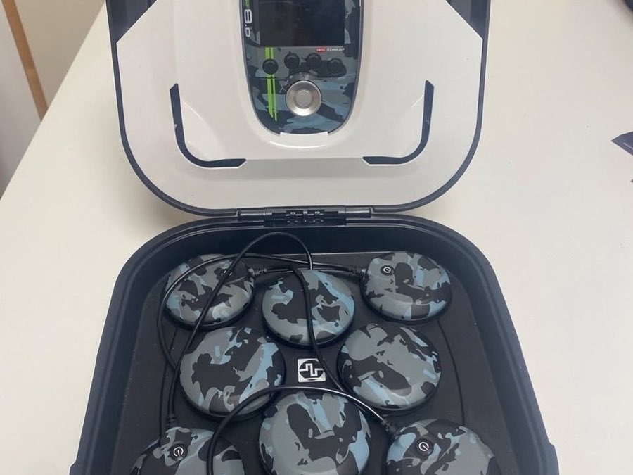 Mallette rigide du Compex SP 8.0 ouverte, boîtier sur son socle et modules de stimulation sans fil dans leur plateau