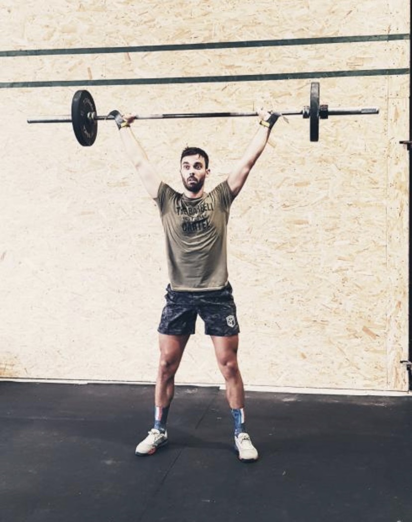 Gabin en réception d'arraché pendant un WOD, maniques aux mains, barre verrouillée au-dessus de la tête