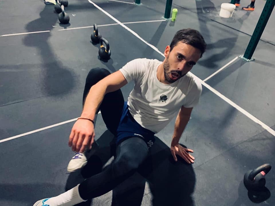 Gabin assis au sol à la fin d'un WOD, entouré de kettlebells, lors d'une compétition interne